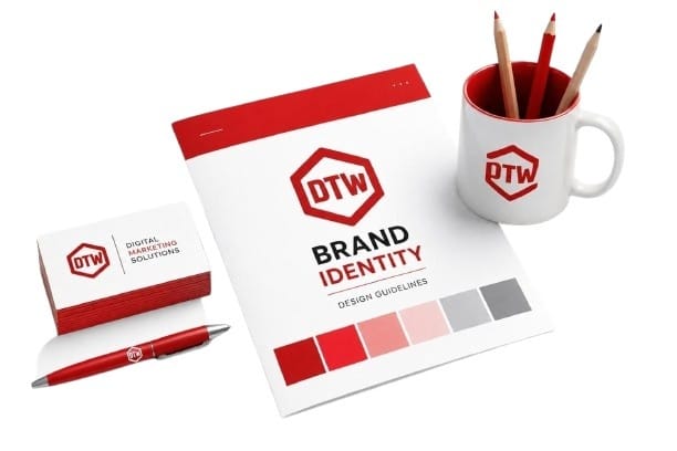 Professional DTW brand identity mockup featuring a red hexagon logo, business cards, pen, mug, and branding booklet in #B60000 color on a clean white background.